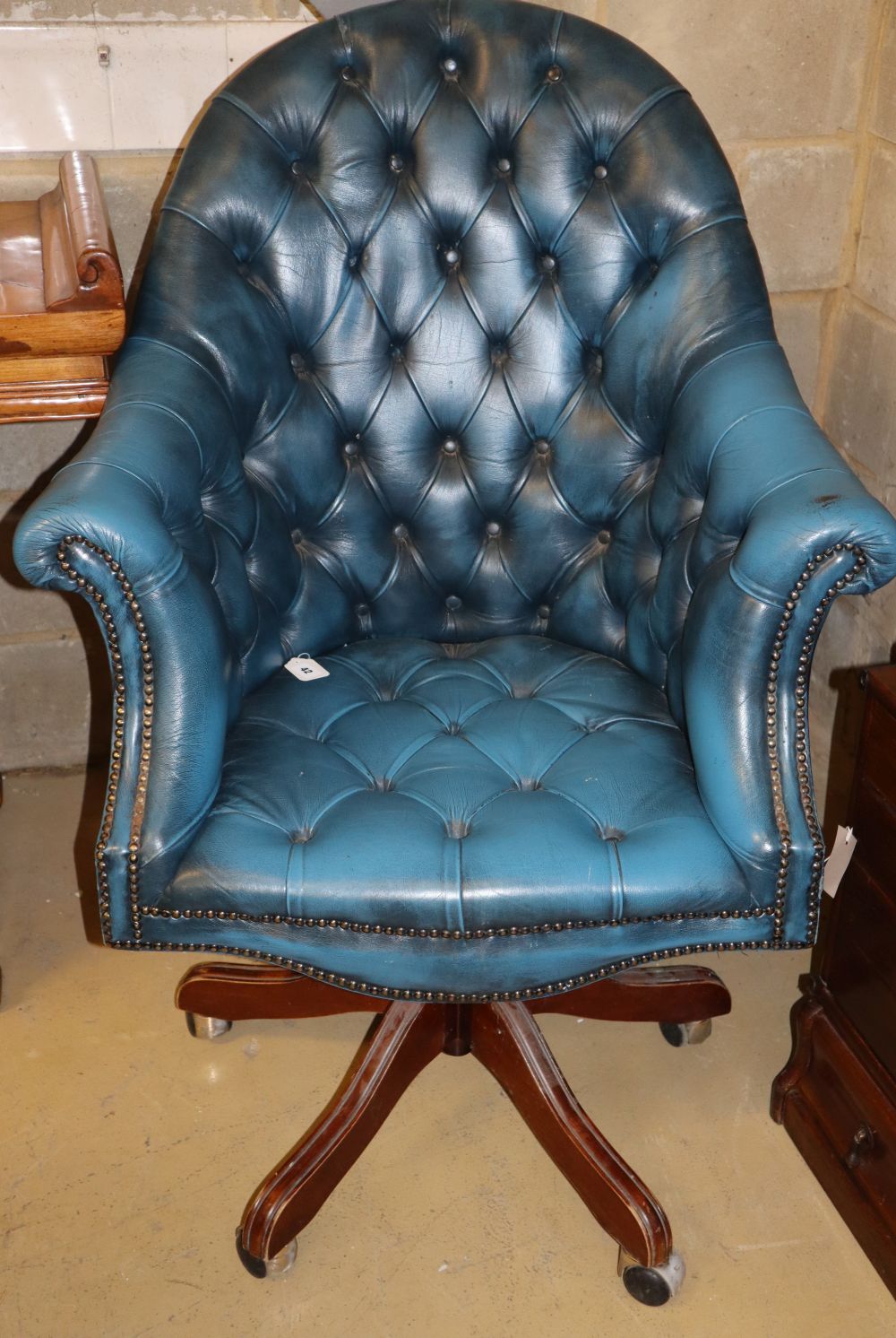 A buttoned blue leather upholstered swivel desk chair